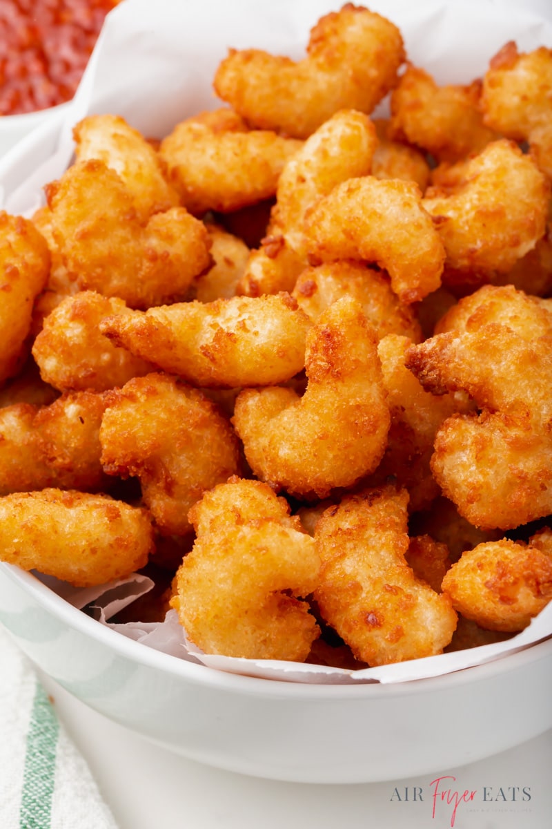 a white bowl filled with crispy air fryer popcorn shrimp