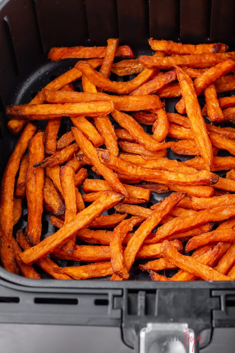 a black air fryer basket filled with crispy frozen sweet potato fries
