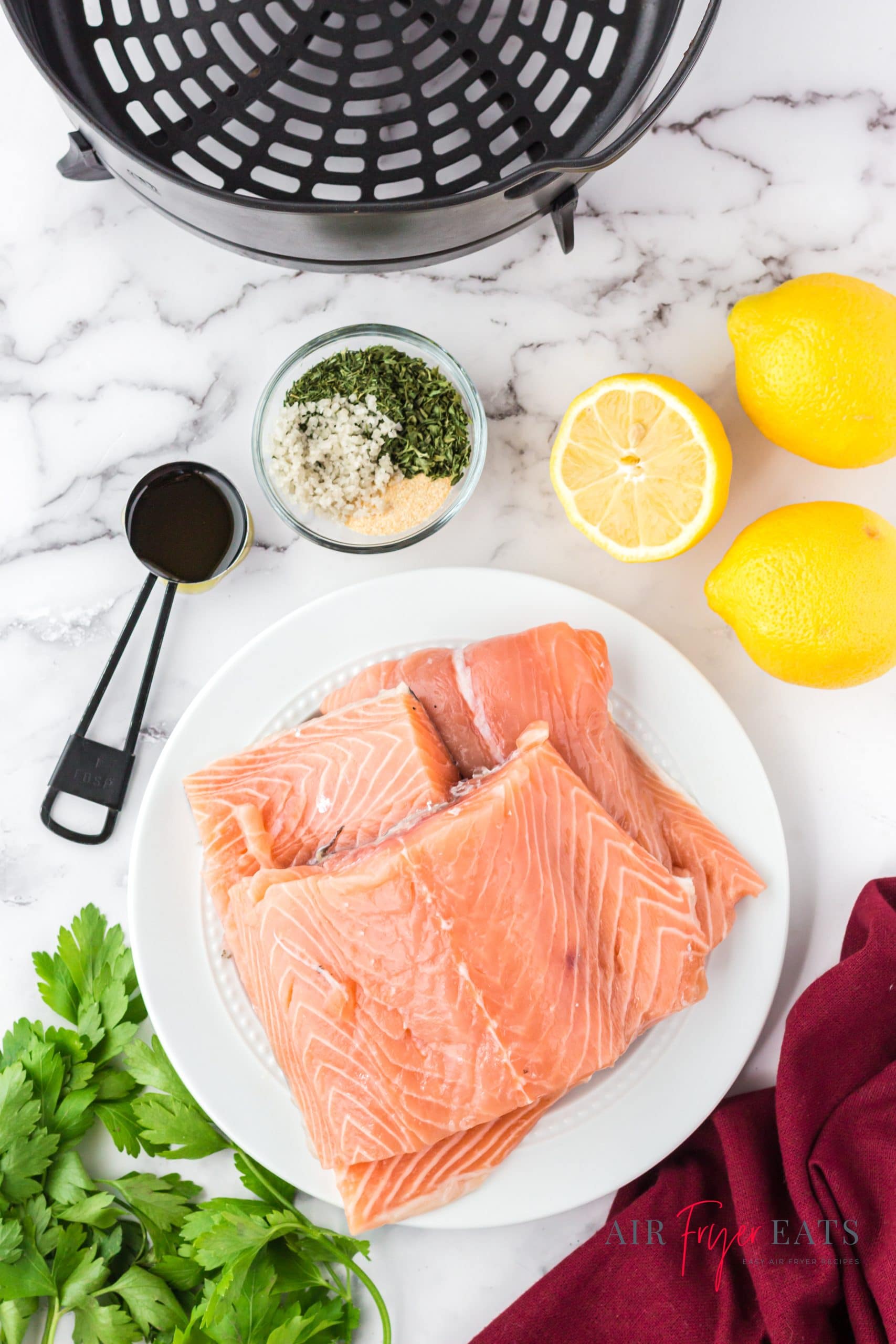 Ingredients needed to make salmon in ninja foodi, including raw salmon filets, lemon, and seasonings
