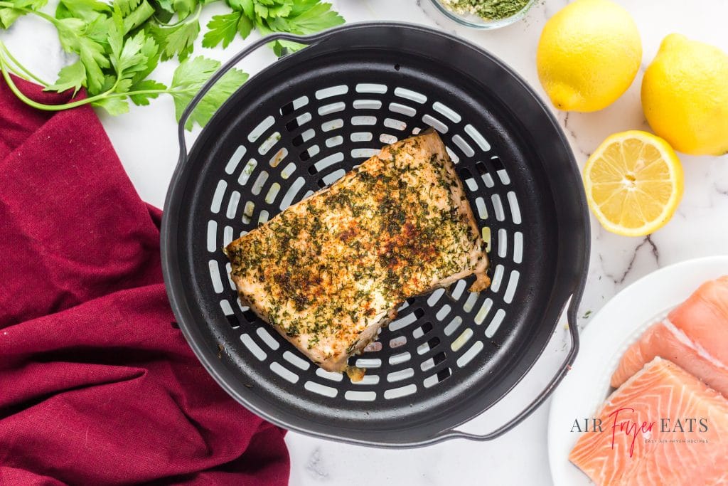 A cooked salmon filet in an air fryer basket