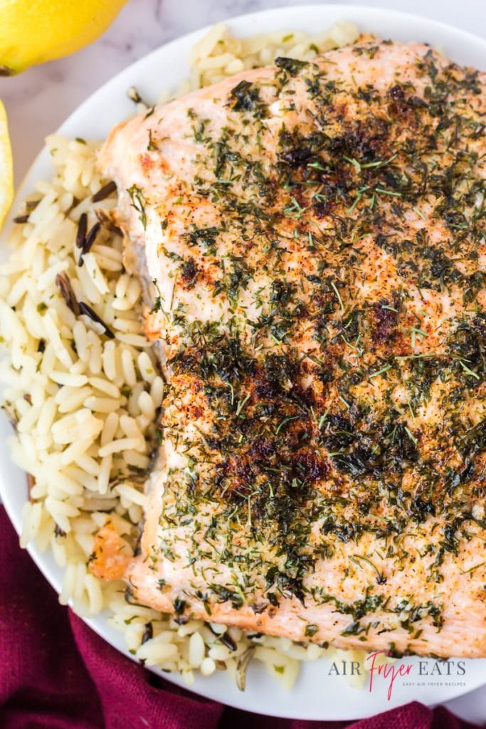 Cooked salmon filets with parsley on top of a plate of rice pilaf.