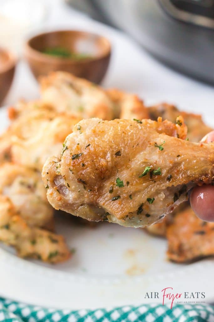 a plate of mild chicken wings with one drumette held up for the camera