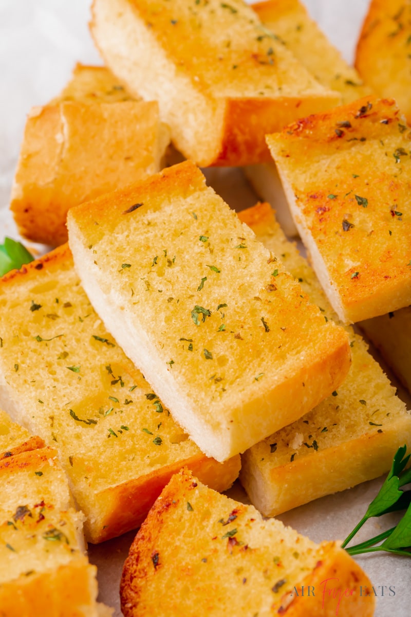 rectangular slices of garlic bread stacked up on a plate