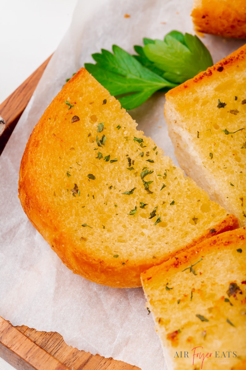The curved end piece of a garlic bread loaf on a plate.