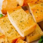 rectangular slices of garlic bread stacked up on a plate