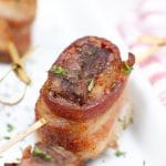 Close up photo of a bacon wrapped steak bite being held up on a toothpick