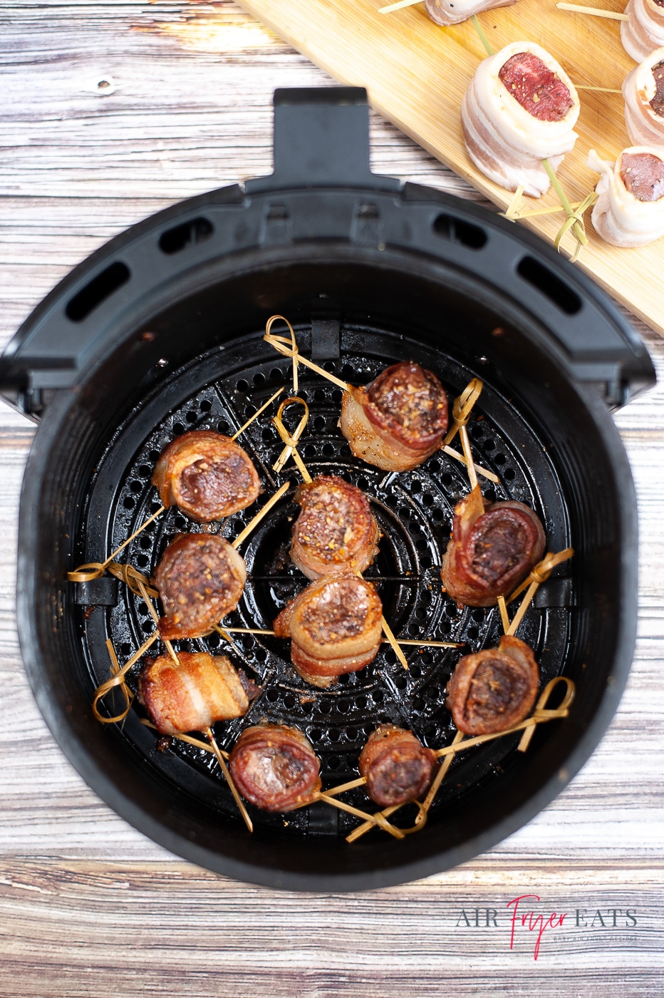 Vertical overhead shot of bacon wrapped steak bites say in a black air fryer basket