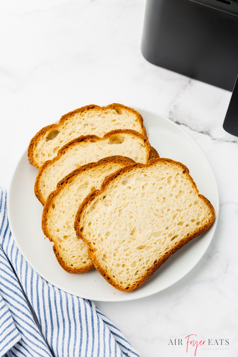 four slices of white bread on a plate next to an air fryer