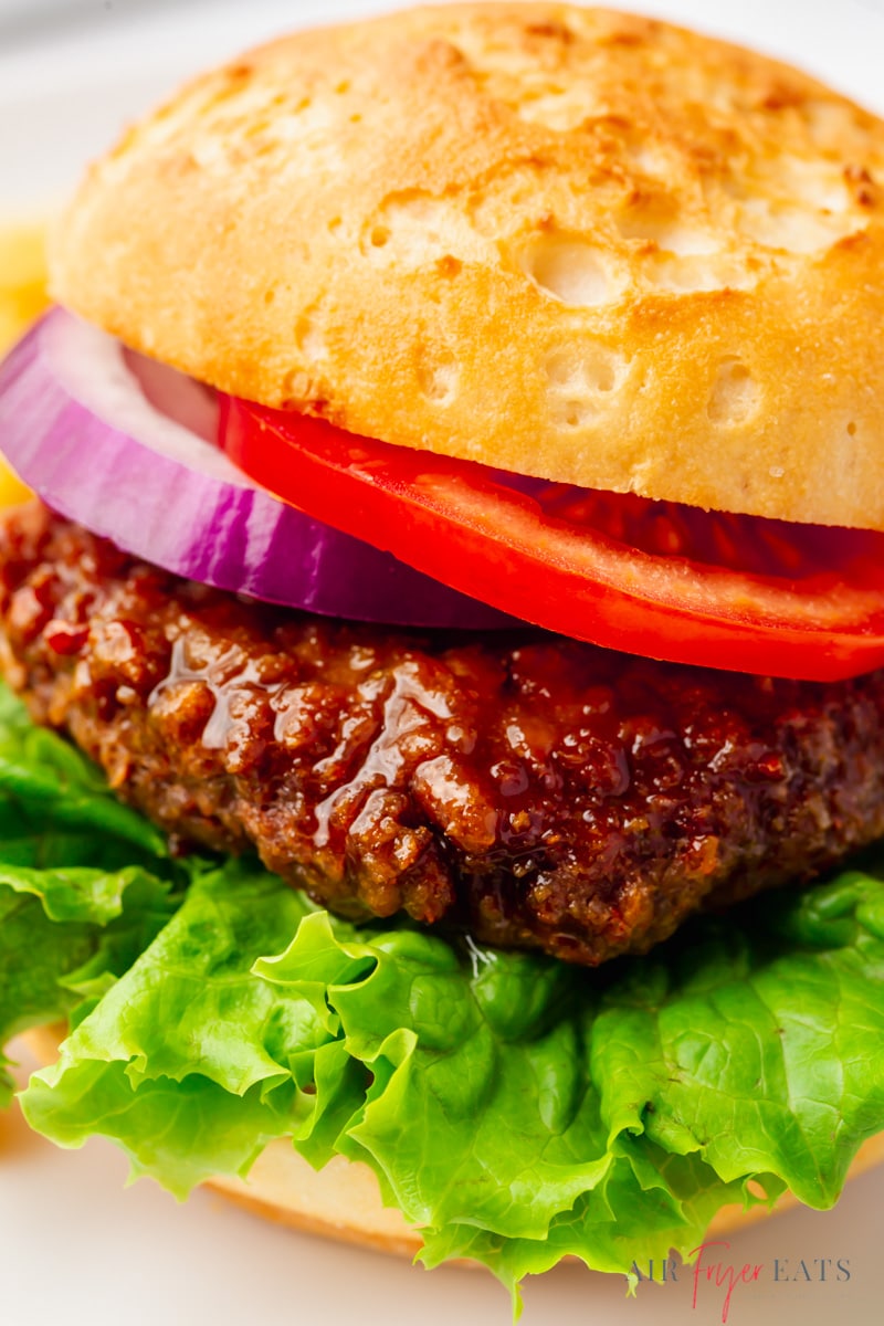 A beyond burger on a bun with leaf lettuce, tomato, and red onion