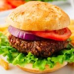 A beyond burger on a bun with leaf lettuce, tomato, and red onion
