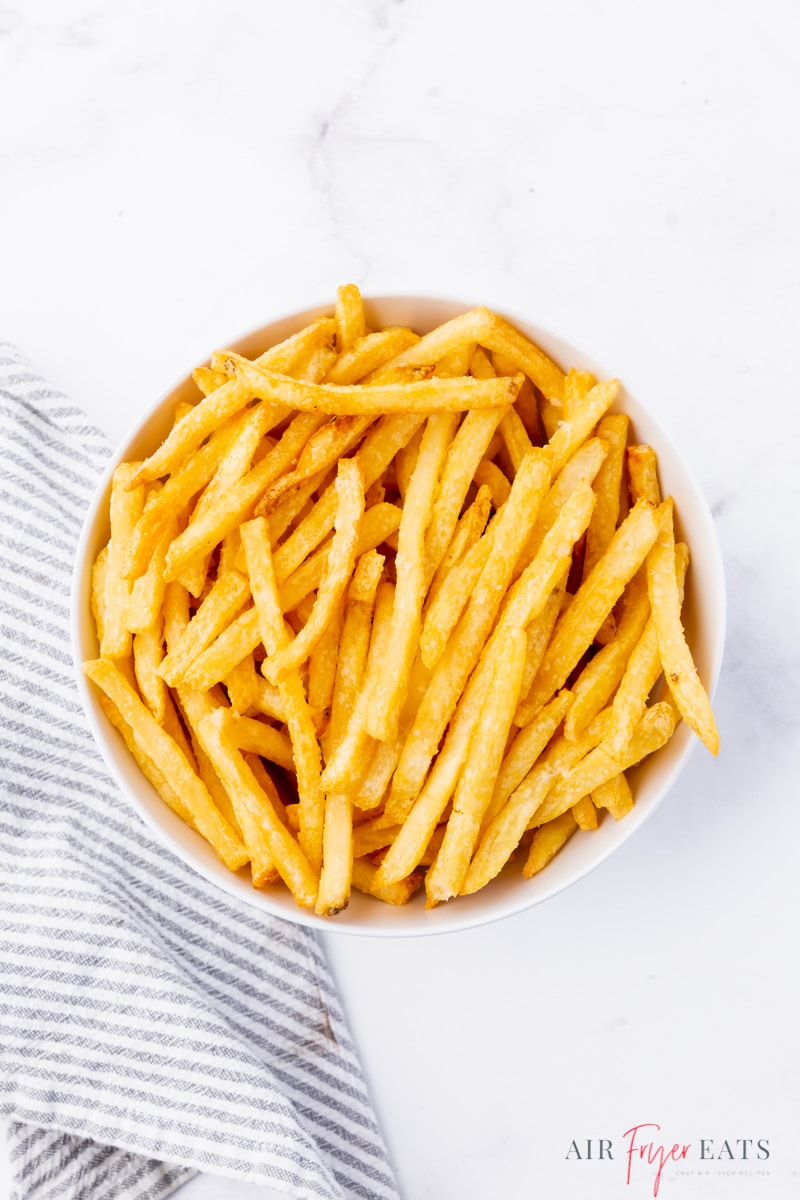 a white bowl of cold french fries, viewed from above.