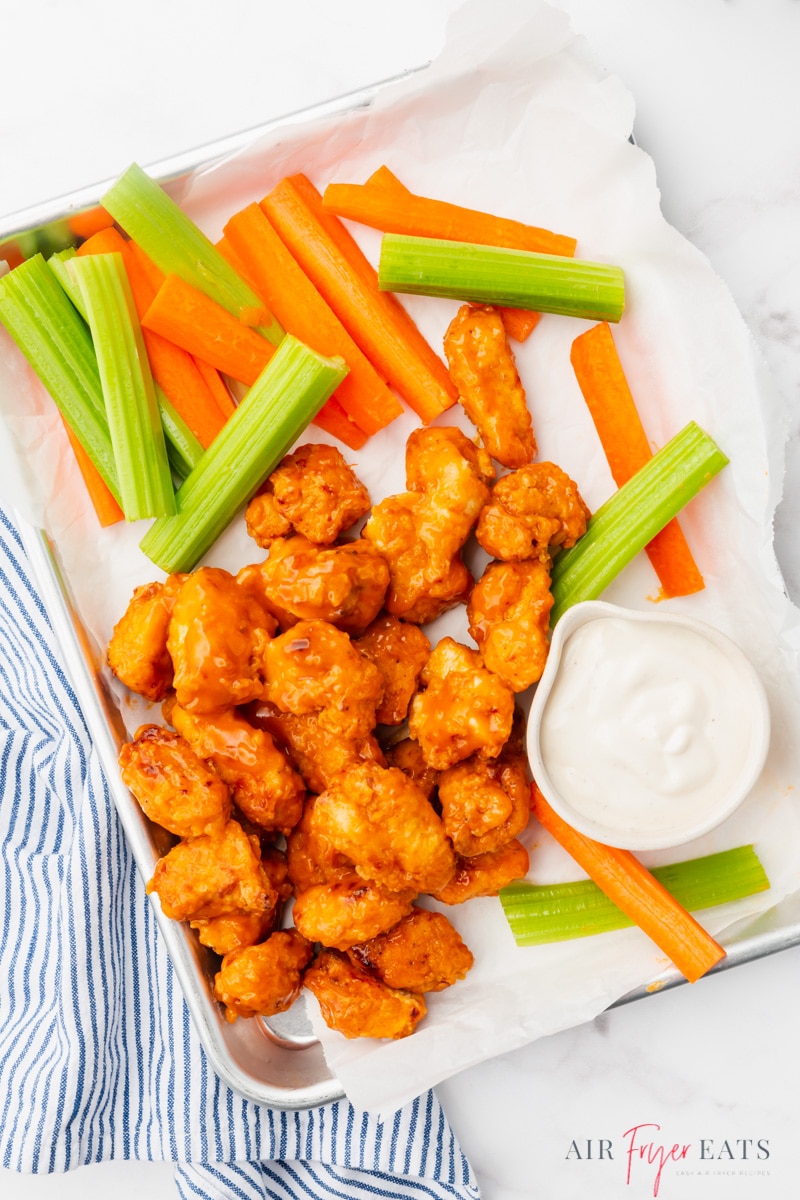 a rectangle platter of homemade air fryer buffalo boneless wings with a side of dip and carrot and celery sticks