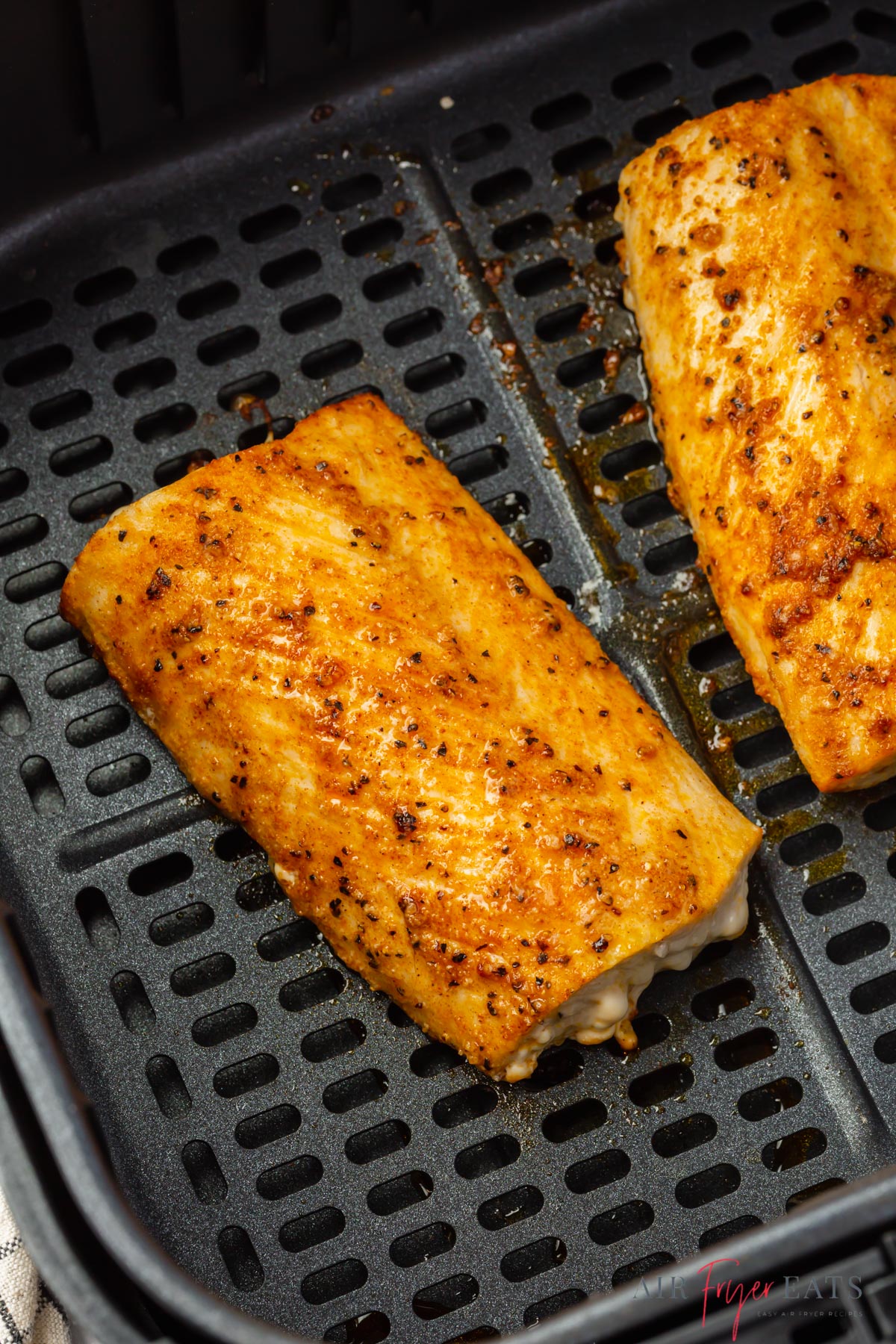 seasoned, cooked mahi mahi fillets in a black, square air fryer basket