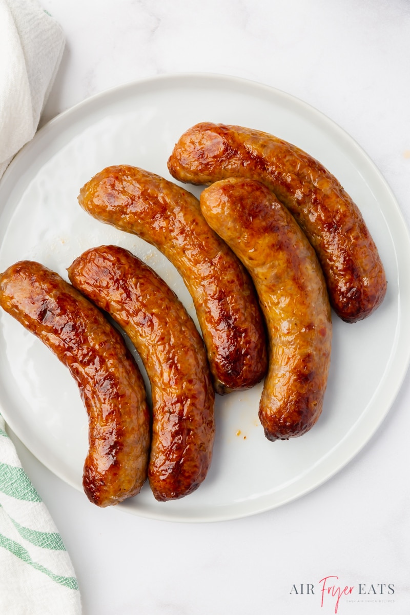 a round white plate filled with 5 air fried sausages. 
