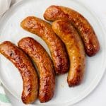 a round white plate filled with 5 air fried sausages.
