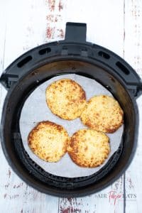4 Cooked pizza bases in a black air fryer backet