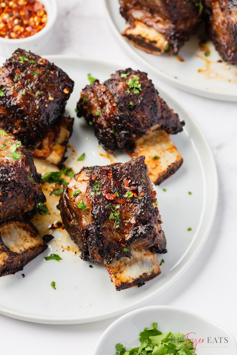 a white plate of 4 english cut beef short ribs cooked in air fryer. 