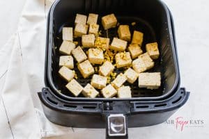Cubed tofu in black air fryer basket