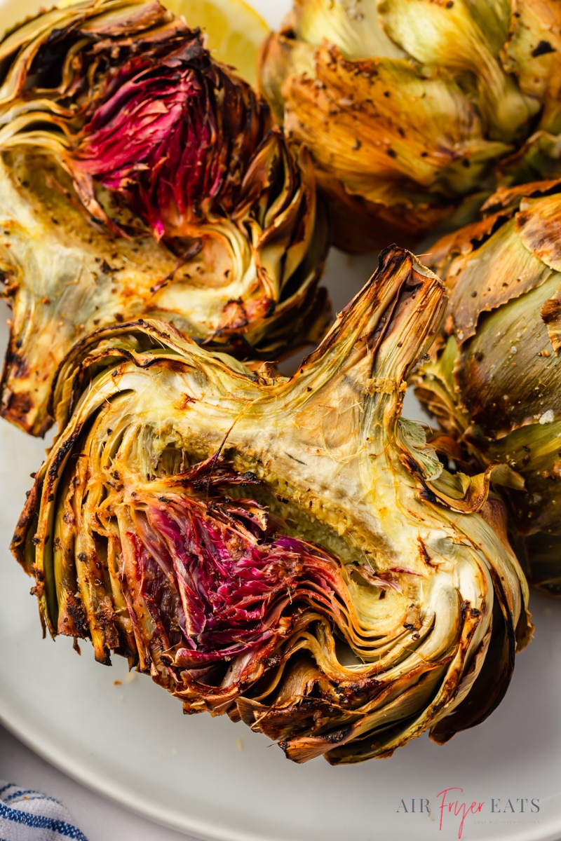 a closeup shot of roasted air fryer artichoke halves on a plate.