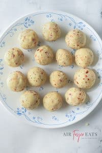 Mashed potato and seasonigs rolled into 14 balls on a white plate