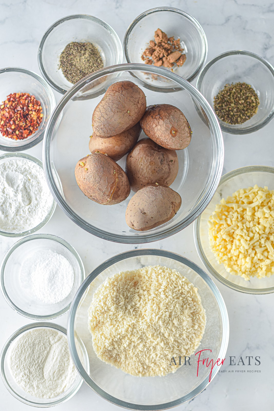 A vertical photo of various glass bowls containing all the ingredients for making air fryer cheesy potato balls