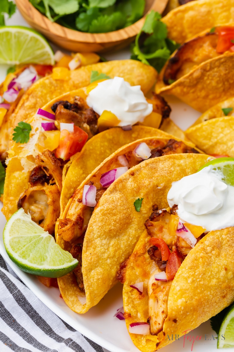 Chicken tacos in homemade taco shells topped with pico, sour cream, lime wedges.