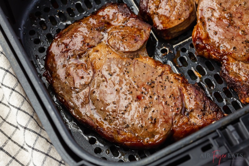 a cooked steak in a square air fryer basket