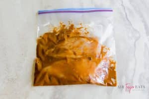 A ziploc bag containing chicken breasts and mustard mixture