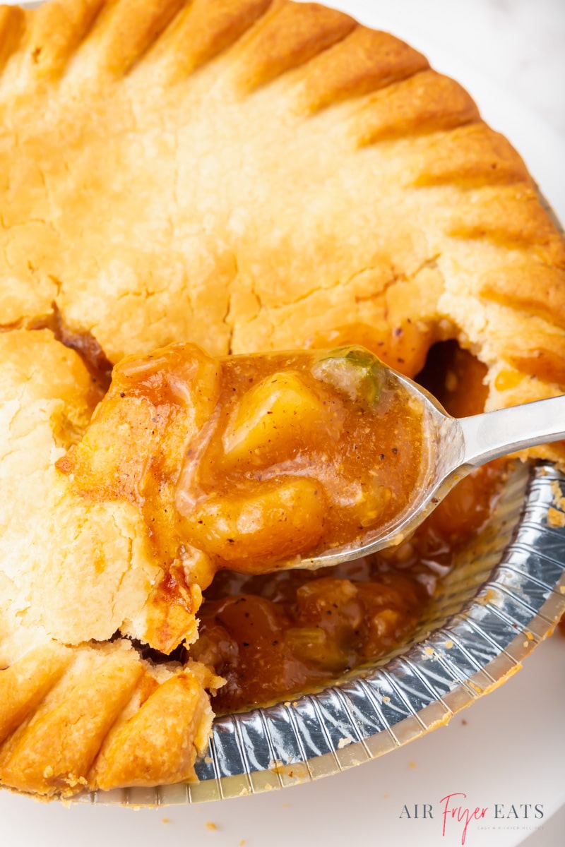 a cooked pot pie made in the air fryer. A spoon is eating it directly from the pan. 
