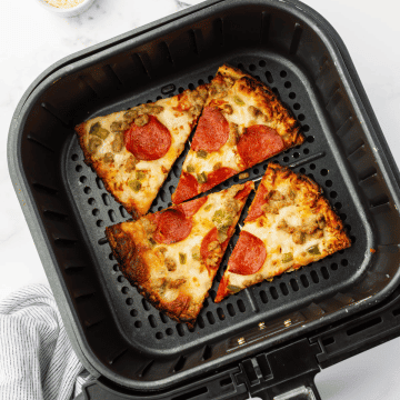 four slices of leftover pizza in a cosori air fryer basket, viewed from above
