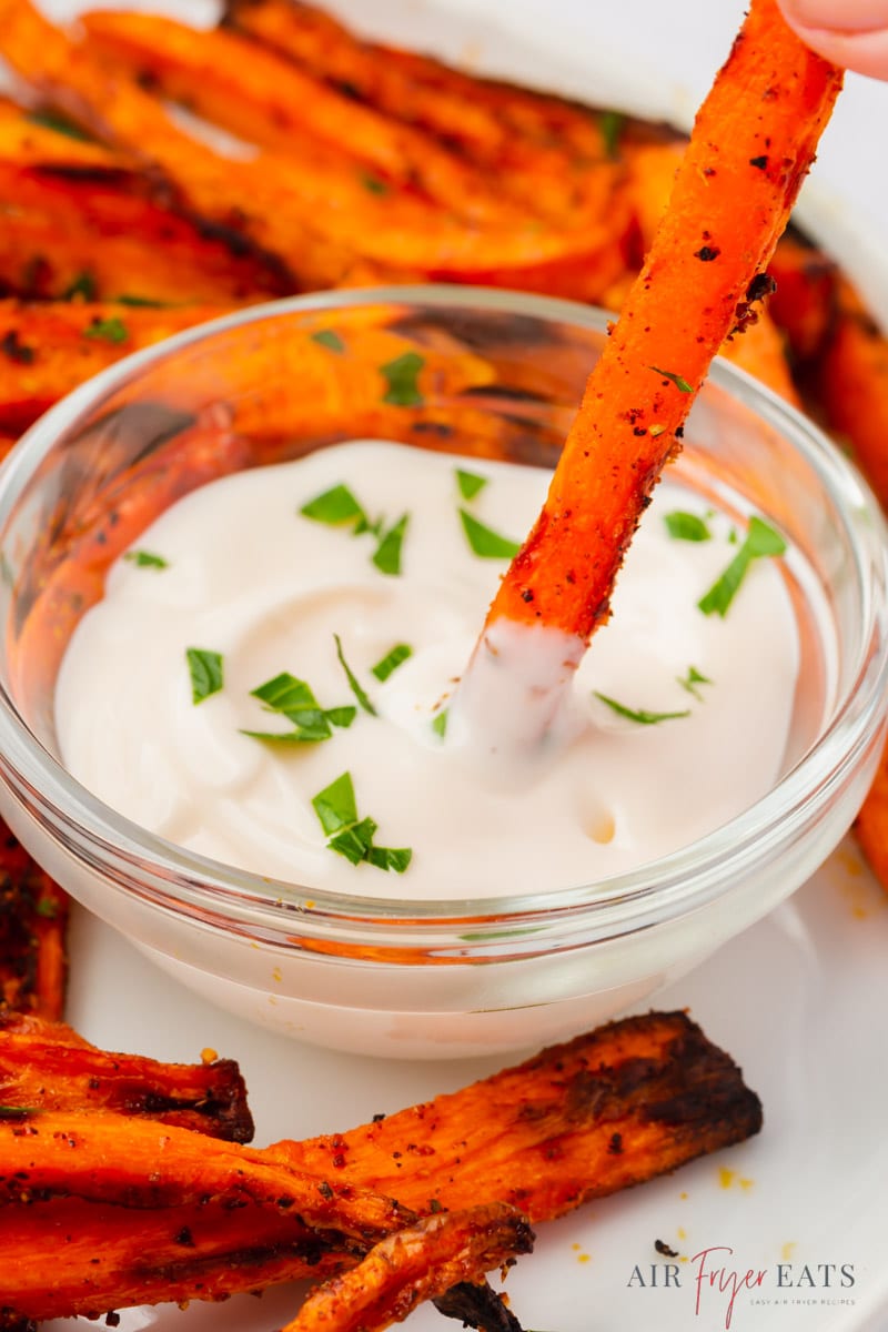 carrot frie dipping into a small glass bowl of ranch dressing