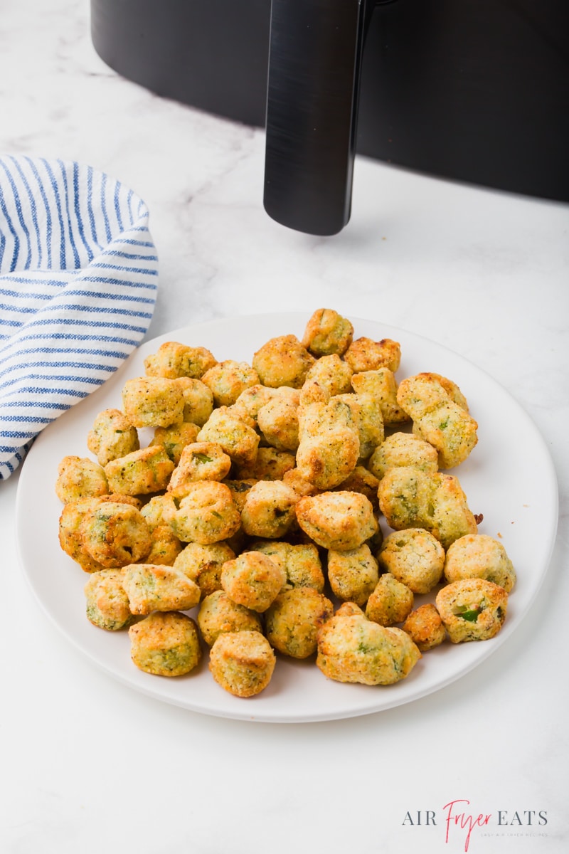 a plate of cooked frozen okra in front of a cosori air fryer.