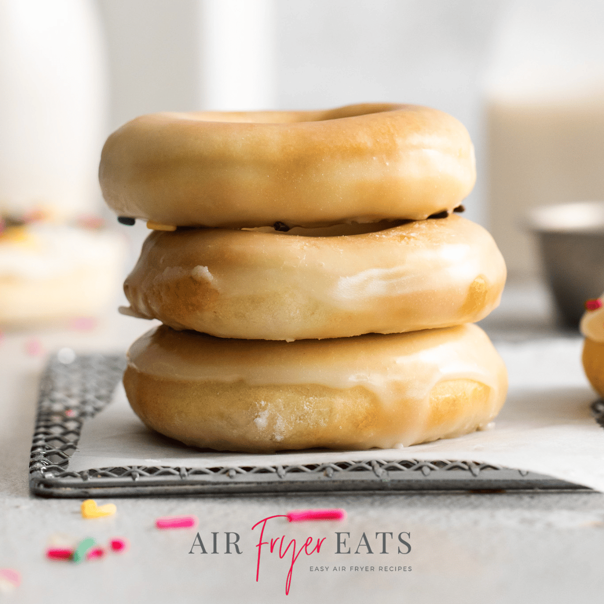 Photo of a stack of 3 glazed Air Fryer Donuts, on a cooling rack and ready to eat.