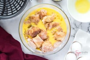 a bowl with cut chicken coated in flour and spices with beaten eggs added