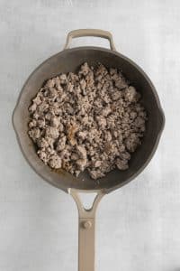 Top view photo of ground pork in a frying pan, sautéed until cooked through.