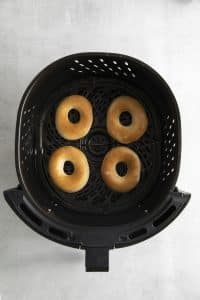 Top view photo of 4 Air Fryer Donuts, in the air fryer basked and fully baked.