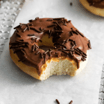 Photo of an air fryer doughnut with a bite taken out of it. It's covered in chocolate frosting and sprinkles.