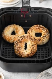 Photo of three Air Fryer Bagels in the air fryer basket and fully cooked and golden brown.
