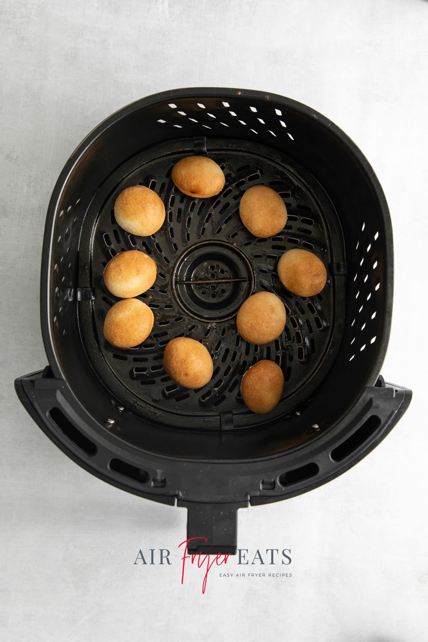 Top view photo of an air fryer basket filled with golden brown donut holes.