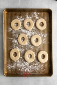 Top view photo of air fryer doughnut dough, in a doughnut shape, on a floured baking sheet.