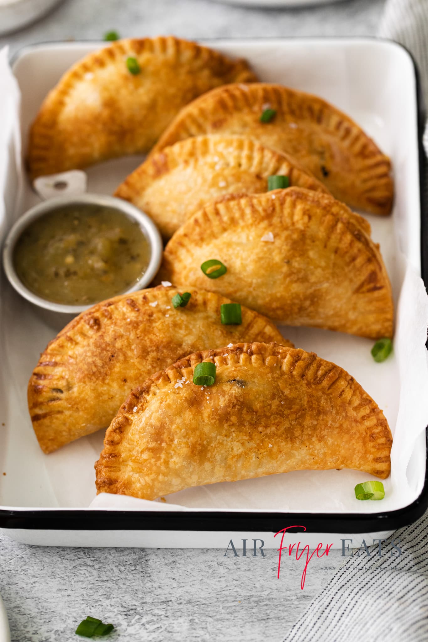 Photo of Air Fryer Empanadas on a white serving platter with a dipping sauce on the platter as well.