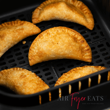 Closeup photo of crispy, golden Air Fryer Empanadas in the air fryer basket.
