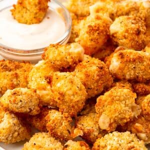 a plate of crispy cheese curds with a small bowl of ranch dressing on the side.