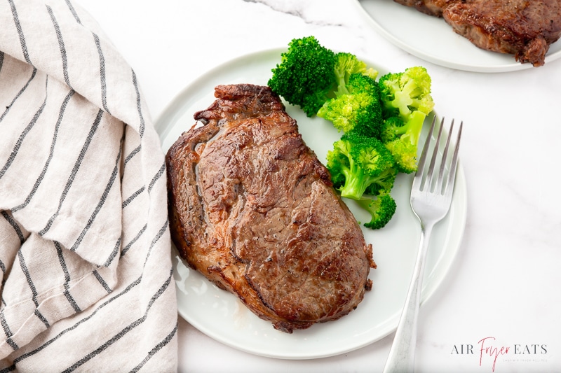 a dinner plate with air fryer reheated steak and steamed broccoli.