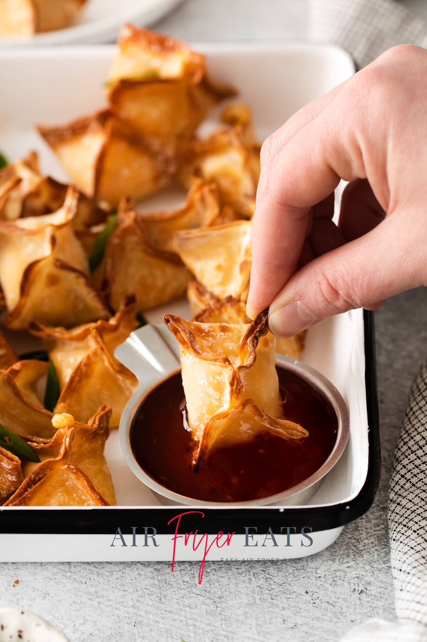 Photo of an Air Fryer Wonton being dipped in sweet and sour sauce. 