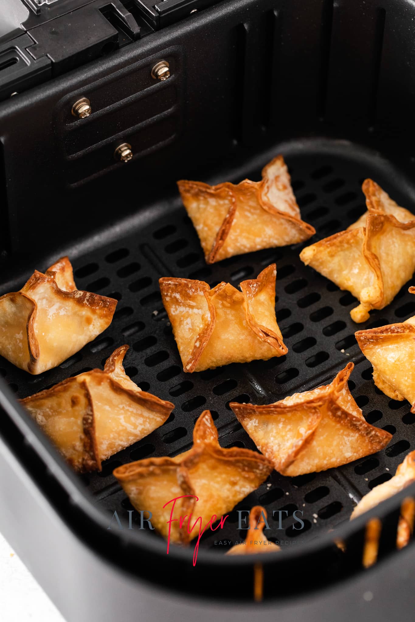 Closeup photo of golden brown Air Fryer Wontons in the basket of the air fryer. 