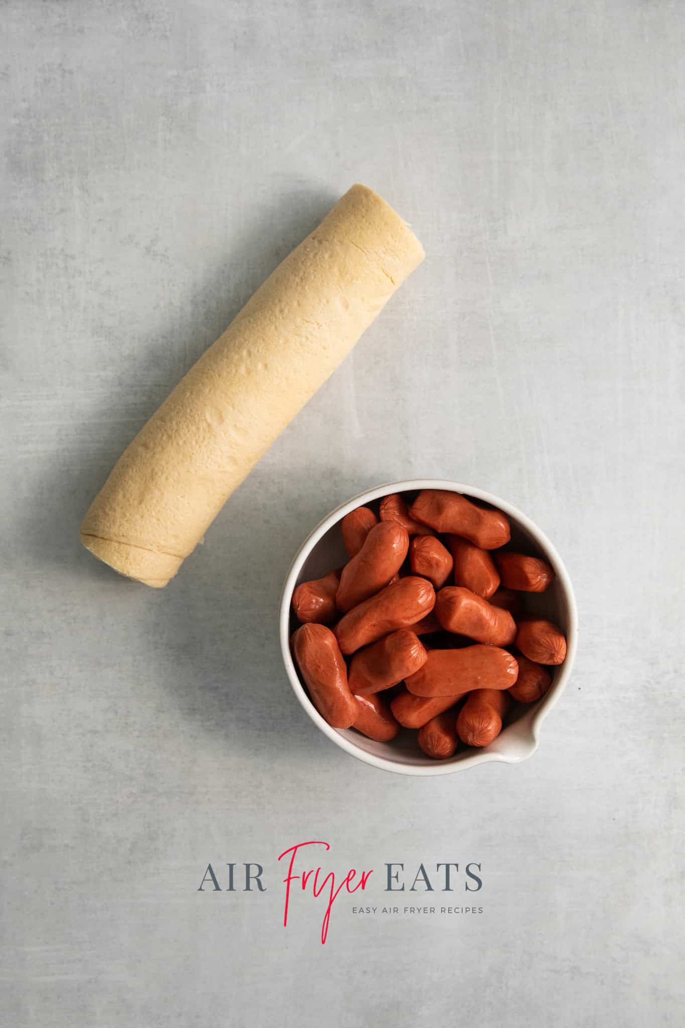Top view photo of the ingredients needed to make Air Fryer Pigs in a Blanket, including pastry and miniature hot dogs. 