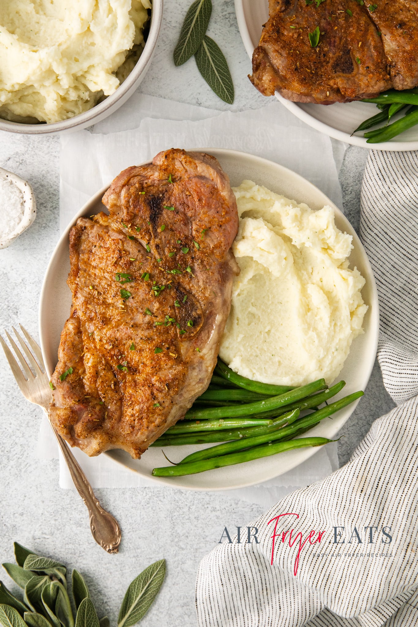 Top view photo of a plate with an Air Fryer Pork Steak, mashed potatoes, and green beans, ready to enjoy. 