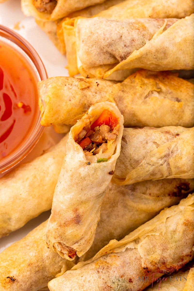 closeup of a plate of air fryer lumpia rolls with a side of sweet and sour sauce.