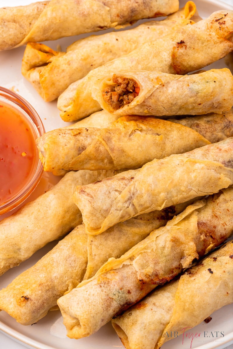 closeup of a plate of air fryer lumpia rolls with a side of sweet and sour sauce.